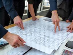People collaborating on a blueprint or plan, symbolizing custom design.